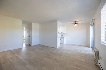 An empty living room and kitchen with a ceiling fan